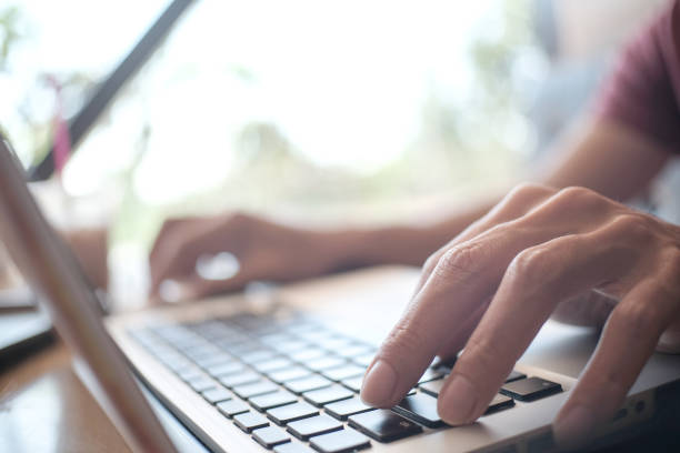 istock Man working by using a laptop computer on wooden table. Hands typing on a keyboard 1341702520