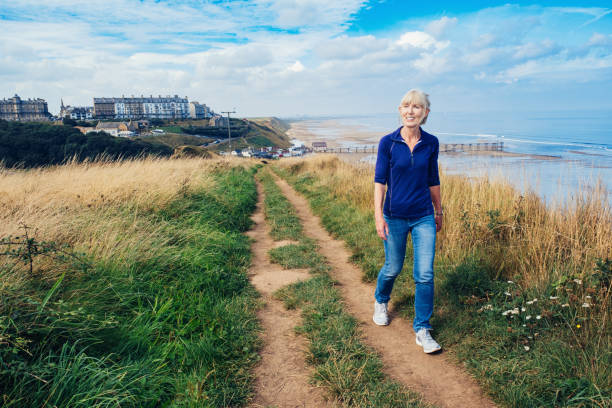 Woman walking the Cleveland Way long distance footpath above the village of Saltburn, North Yorkshire Region, England.