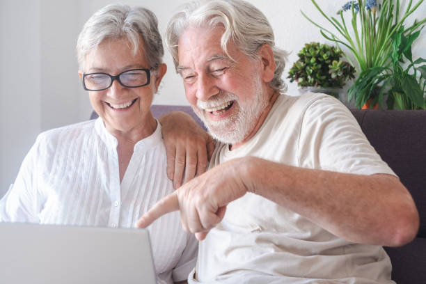 istock Beautiful senior couple  using laptop computer laughing. Serene elderly people enjoying technology and social 1341710927