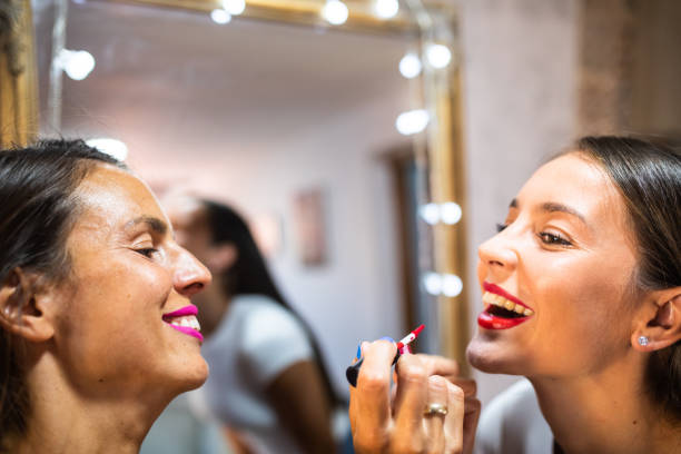 istock A young woman smiling while her friend is applying her lipstick 1341711420