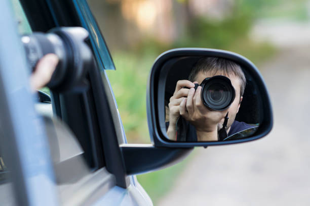 istock A man is taking photo someone or something from an open car window. Reflection in the side mirror of the car 1341712361