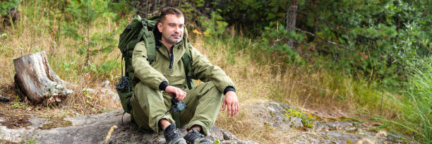istock Young man travelling alone with a backpack. Concept of active tourism, camping in the forecast, trekking and hiking during vacations. Green background. Copy space for text 1341712488