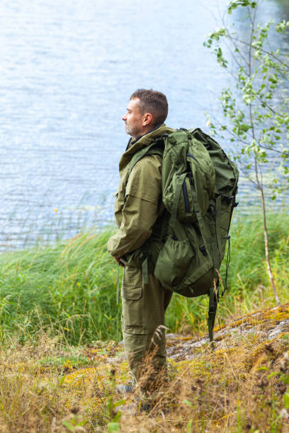 istock Young man travelling alone with a backpack. Concept of active tourism, camping in the forecast, trekking and hiking during vacations. Green background. Copy space for text 1341712539