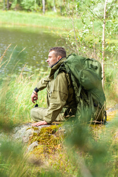 istock Young man travelling alone with a backpack. Concept of active tourism, camping in the forecast, trekking and hiking during vacations. Green background. Copy space for text 1341712554