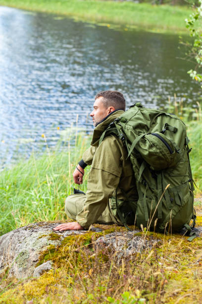 istock Young man travelling alone with a backpack. Concept of active tourism, camping in the forecast, trekking and hiking during vacations. Green background. Copy space for text 1341712555