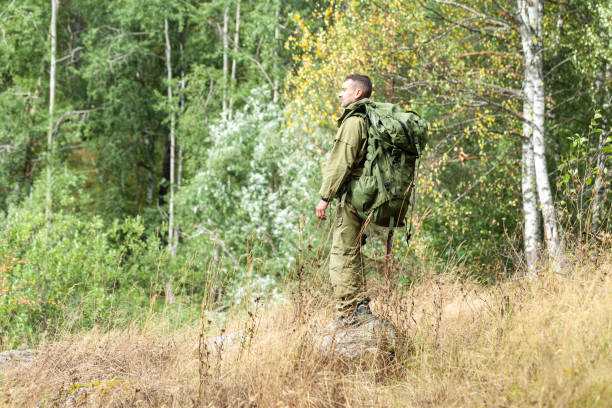 istock Young man travelling alone with a backpack. Concept of active tourism, camping in the forecast, trekking and hiking during vacations. Green background. Copy space for text 1341712579
