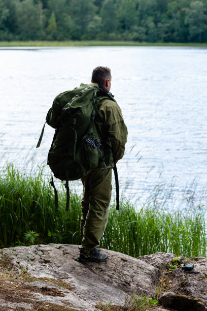 istock Young man travelling alone with a backpack. Concept of active tourism, camping in the forecast, trekking and hiking during vacations. Green background. Copy space for text 1341712687