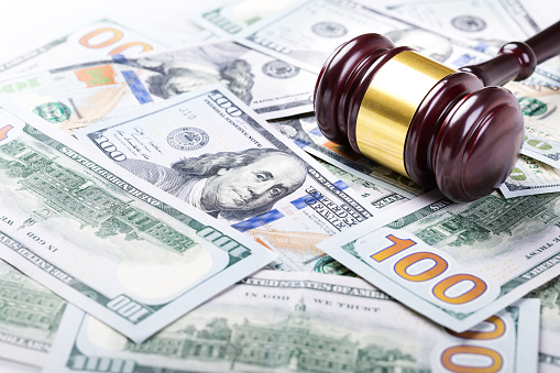 Wooden judge gavel on hundred dollar banknotes background, closeup