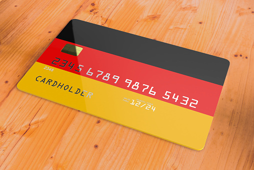 Plastic credit or bank debit card with country flag of Germany national banking system isolated on wooden table close up concept 3d rendering image