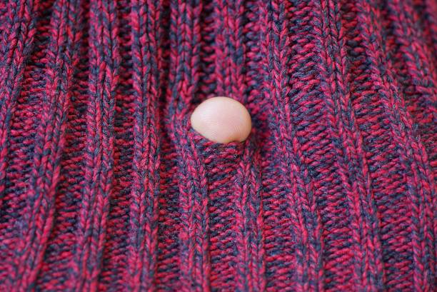 istock one white finger in a hole in torn red woolen fabric 1341715462