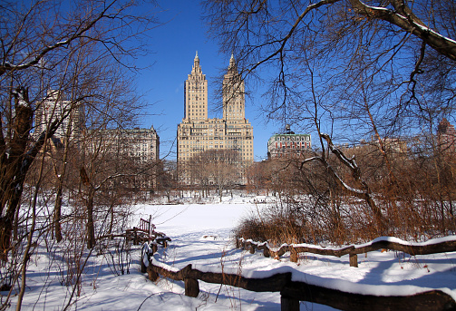 The path to the walkable frozen lake with the two towers building on the back in Central Park