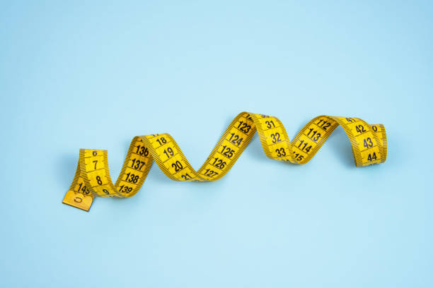 istock Yellow spiral tape measure on blue bright background 1341716198