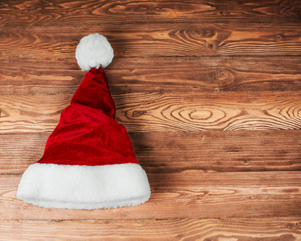 istock Santa's red hat lies on a wooden brown background. 1341717552