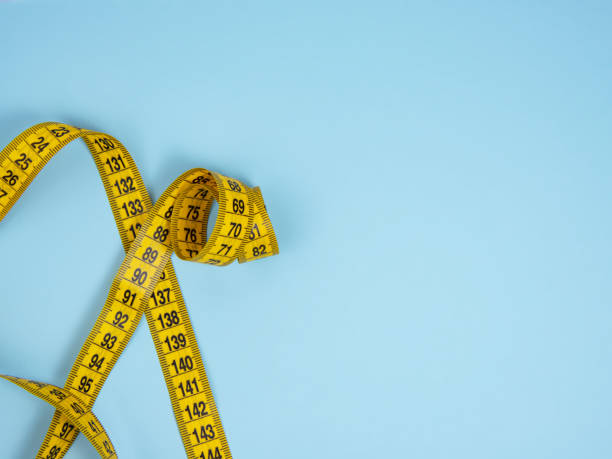 istock Yellow spiral tape measure on blue bright background 1341718460