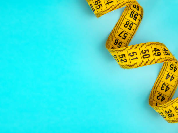 istock Yellow spiral tape measure on blue background 1341719126