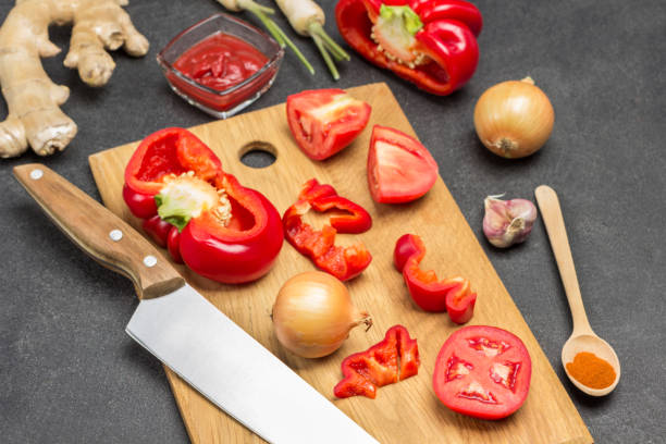 istock Red pepper, tomato and knife on cutting board. 1341720643
