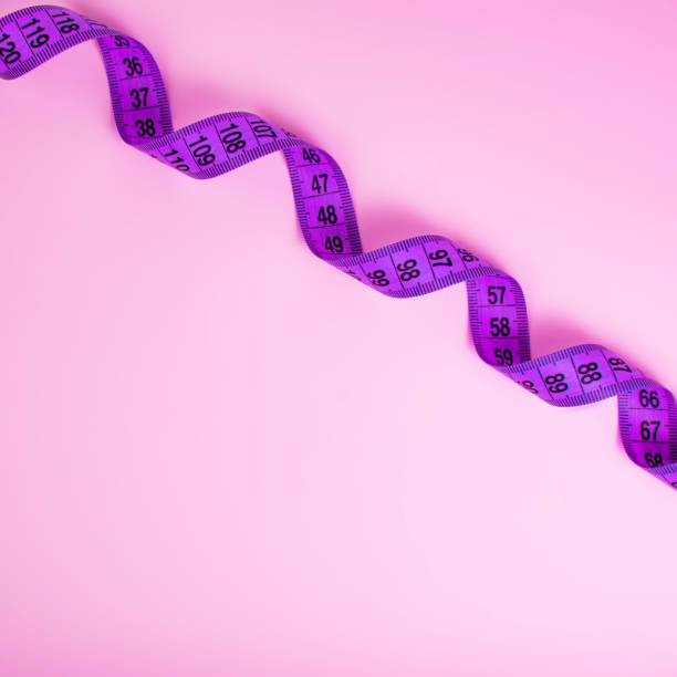 istock Bright purple tape measure on violet background with copyspace 1341721333