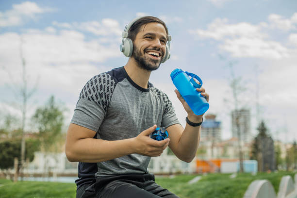 istock Young man in sportswear is drinking water after jogging 1341721544