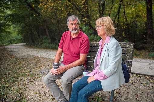 Shot of a senior Caucasian couple enjoying coffee while sitting on a bench in a public park. Simply enjoying life.