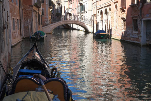 Bow of a gondola seen from above and with a view to a colorful water surface at Canal Grande in the center of Venice