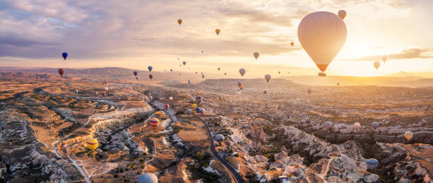 Hot air balloons flying above Göreme, Cappadocia (Kapadokya) Anatolia, Turkey at sunrise. Panoramic view of villages and fairy chimneys. Popular touristic destination for summer vacation holidays stock photo