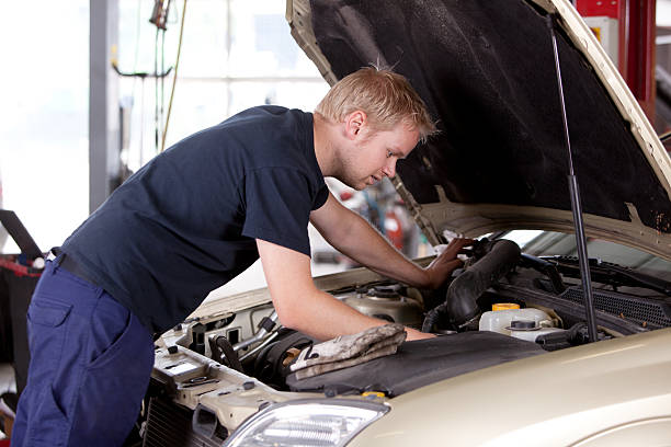 Mechanic fixing old car engine A young mechanic under the hood of a car doing repairs mechanic working under car stock pictures, royalty-free photos & images