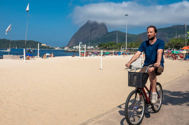 un homme fait du vélo sur la piste cyclable praia do flamengo - parc flamengo photos et images de collection