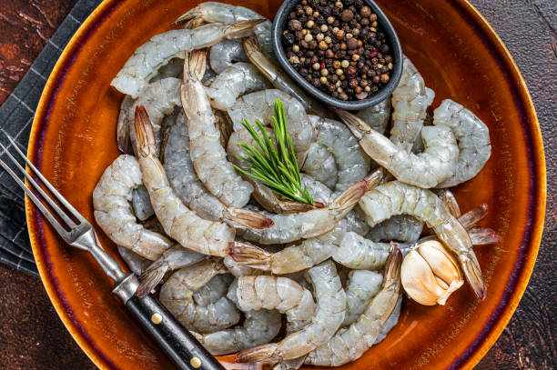 istock Black Raw uncooked Headless giant shrimps prawns in a rustic plate. Dark background. Top view 1341733764