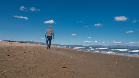 Senior man walking on the beach in winter. Natural beach concept.