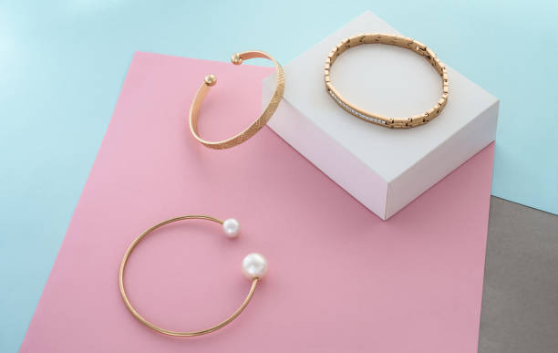 istock Three modern gold bracelets on pastel colors paper background with copy space 1341737130