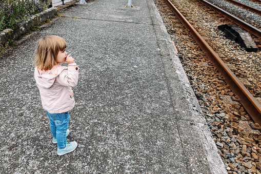 Little girl standing near the railroad tracks. Little girl Age 2 Years watching the Railway Tracks