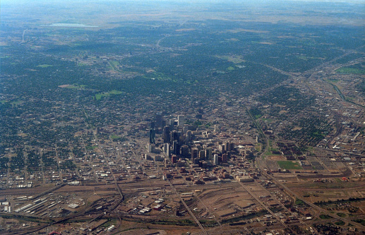 In the summer of 1986, an aerial photo looks southeast showing the South Platte River, downtown Denver, Colorado skyscrapers, Auraria Campus and the Union Station railroad train freight yards with the 23rd Street viaduct where Coors Field baseball stadium now stands.