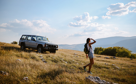 Young woman on a road trip in the beautiful nature, relaxing, using an all terrain vehicle for sightseeing.