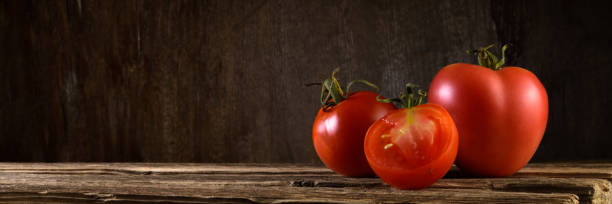istock group of ripe fresh tomatoes on old boards against a brown wooden backdrop. panoramic side view. artistic still life in simple rustic style with copy space 1341749770