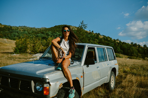 Young woman on a road trip in the beautiful nature, relaxing, using an all terrain vehicle for sightseeing.