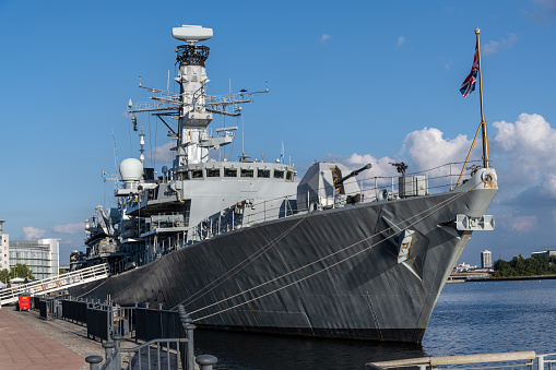 The frigate HMAS Arunta (right), destroyer HMAS Sydney (centre) and amphibious assault ship HMAS Canberra (left) of the Royal Australian Navy.  They are docked at Garden Island, Sydney Harbour, in preparation for an open day to the public during Navy Week, the first open day since the Covid pandemic.  A shadow from a skyscraper in the central business district is starting to make a shadow on the hull of HMAS Canberra.   This image was taken at sunset from Woolloomooloo Bay on 25 February 2023.