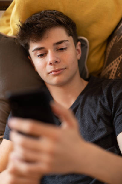 Latin american teenager boy with smart phone at living room stock photo
