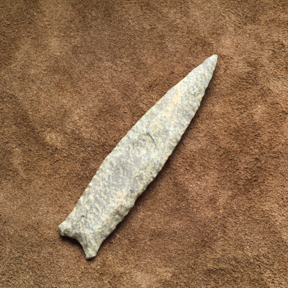 A stone spearhead on leather. This tool would have been attached to a wooden spear and used for hunting by various mid-Paleo Indians across North America.
