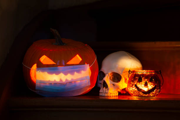 istock Lighted Halloween pumpkin Jack-o-Lantern with face mask for COVID 19 on steps 1341755296