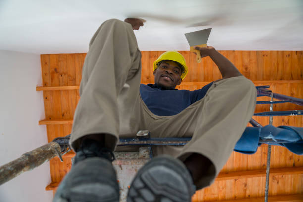 An afro-american worker is plastering an inner wall  during a wood frame house construction
