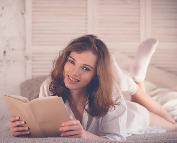 istock lifestyle and people concept:Young woman lying in bed while read 1341765728