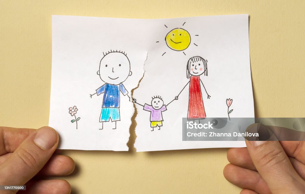 Divorce, relationship difficulties, child problems. A child's drawing, which depicts a mom, dad and a child, is torn in half by man's hands. Divorce, relationship difficulties, child problems. Family Stock Photo