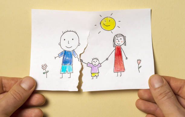 Divorce, relationship difficulties, child problems. A child's drawing, which depicts a mom, dad and a child, is torn in half by man's hands. Divorce, relationship difficulties, child problems. abandoned stock pictures, royalty-free photos & images