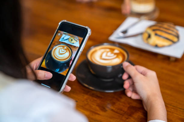 mujer asiática usando la fotografía de teléfono inteligente café con leche y postre en la mesa de la cafetería. - panadería fotos fotografías e imágenes de stock