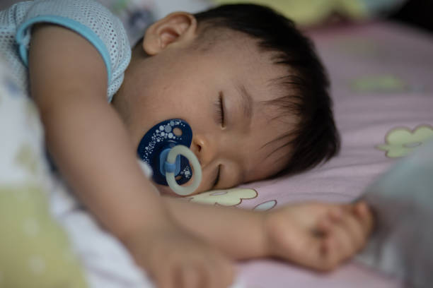 istock Little Asia Chinese child sleeping on bed with sucking pacifier 1341776338
