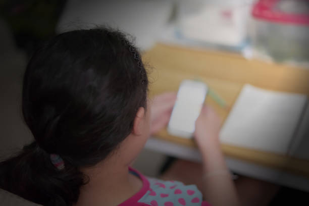 istock A black haired girl is using her mobile phone to search for information. doing homework on the table at home 1341779779