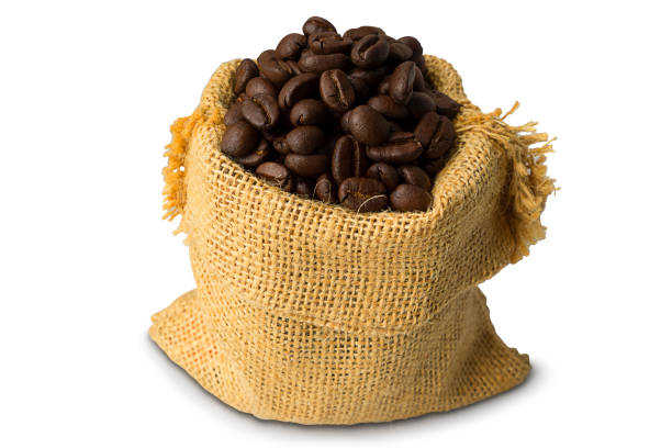 pile de grains de café torréfiés bruns dans un sac isolé sur fond blanc - coffee bean coffee crop sack pouring photos et images de collection