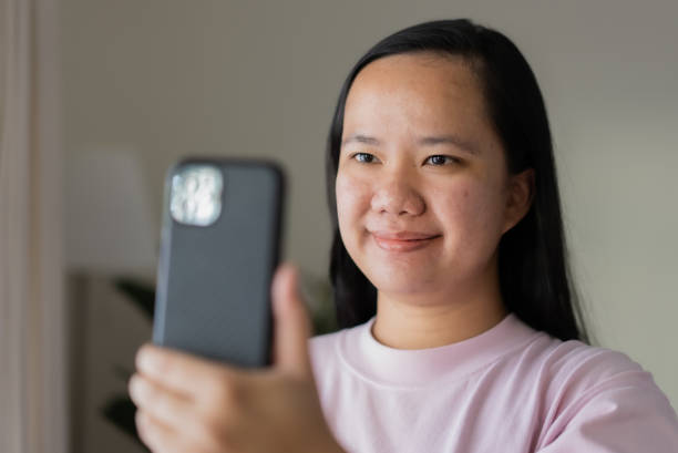 istock Asian woman using mobile phone for video calling with her smile 1341782166