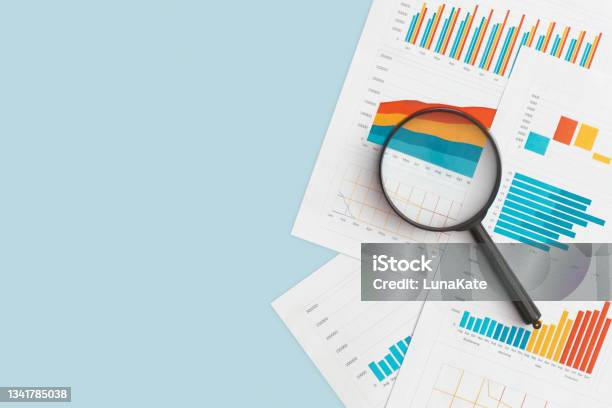 Business Graphs Charts And Magnifying Glass On Table Financial Development Banking Account Statistics Stock Photo - Download Image Now