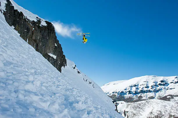 Skier invested in the air. Leaping over the stones, powder snow, off piste. Making a turn in the air.